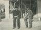 CLARK, Roy Allen (1884-1963)- Seated at his gas station with his apparent pet dog. Person on left is unknown. Gas station was in Burt, Kossuth, IA, USA.